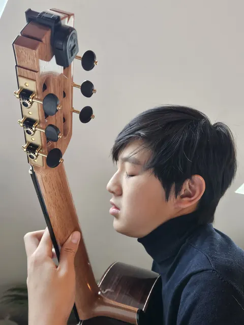 Justin Chen with his classical guitar, eyes closed