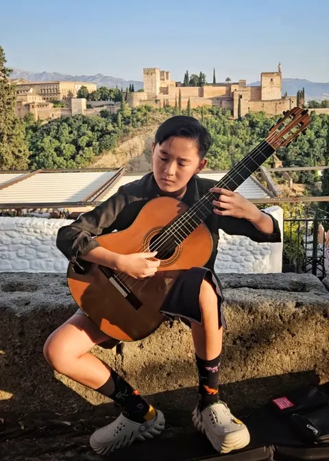 Justin Chen playing classical guitar in view of the Alhambra, Granada